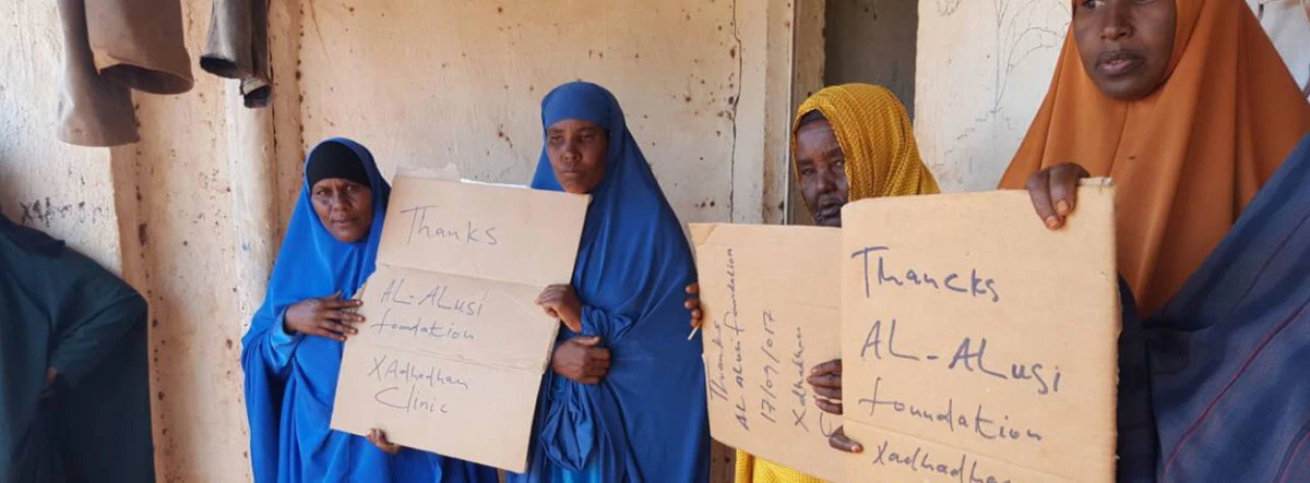 Somali women holding hand-written signs thanking the Alalusi Foundation